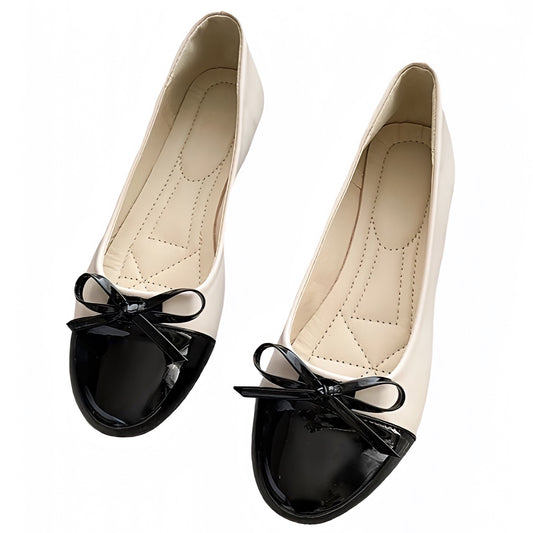 Cream white and black faux patent leather ballet flats featuring a glossy contrast black toe and delicate bow detail. Smooth, vegan-friendly finish with a soft padded insole, low heel, and round toe silhouette. Elegant and comfy, these classic slip-on shoes blend Parisian chic and old-money fashion. Perfect for work, evening, or travel outfits. Ships globally to US, UK, Canada, Australia, New Zealand, and Europe.
