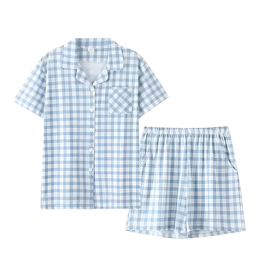 Light blue and white checkered cotton pajama set for women featuring a short sleeve button down collared top with front pocket and matching relaxed shorts. Made from soft breathable cotton blend fabric, this two piece set offers cozy comfort with a classic gingham pattern. Perfect for summer lounging, resort wear, or travel. Inspired by Roller Rabbit and Eberjey. Ships globally to US, UK, Canada, Australia, New Zealand, Europe, and Asia.

