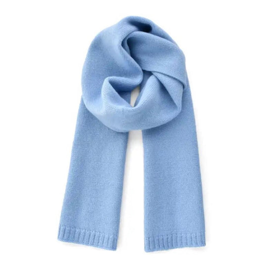 Light blue oversized knit wool scarf for women crafted from a soft plush wool blend yarn. Thick, chunky knit texture with cozy and warm feel, perfect for fall and winter layering. Feminine pastel blue color inspired by Scandinavian street style and minimalist cold-weather fashion. Elegant, versatile, and luxurious knitwear essential. Ships worldwide to US, UK, Canada, Australia, New Zealand, Europe, and Asia.